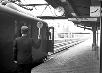 837811 Afbeelding van een perronopzichter die het vertreksein geeft aan de wagenvoerder van een trein richting Nijmegen ...